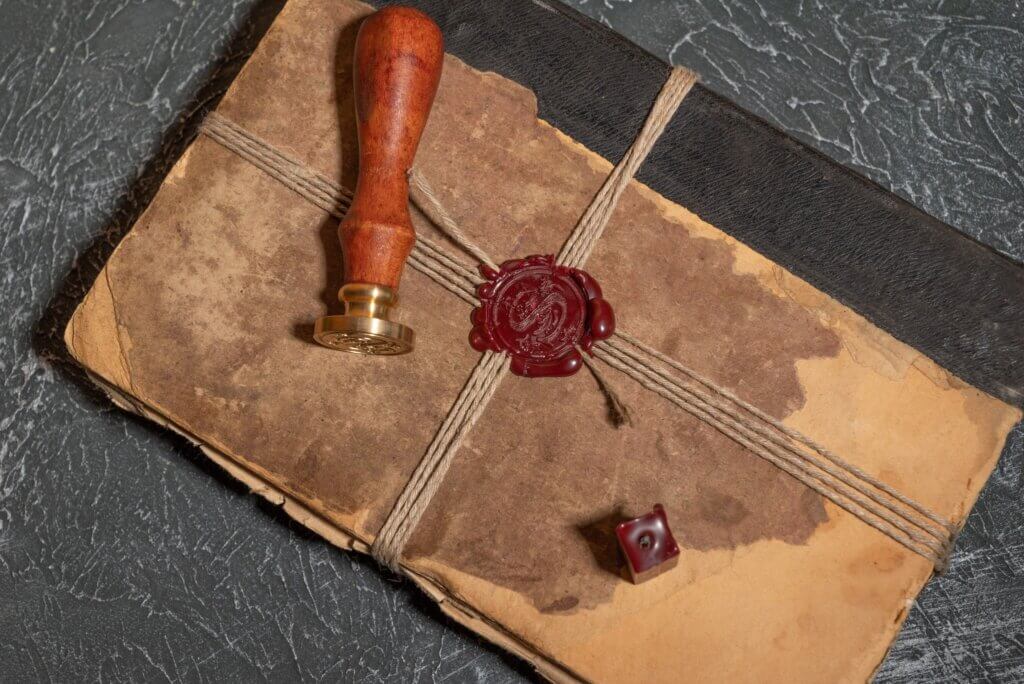 Antique shabby book tied with a thread with a wax seal and a stamp. The concept of secret knowledge