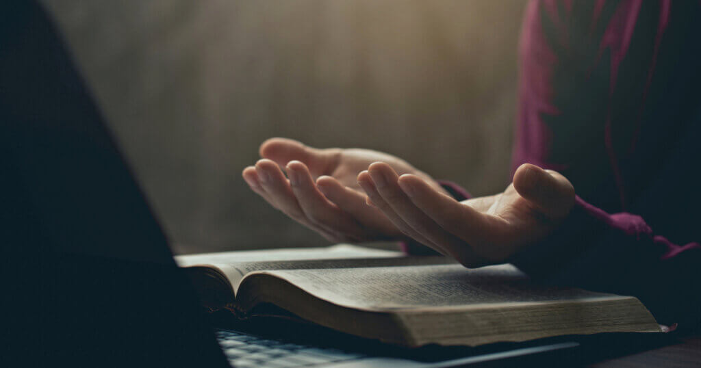 Hands together in prayer for god blessing to wish to have a better life. man hands praying to god with the bible on his laptop. believe in goodness. spirituality and religion, and bible prayer online